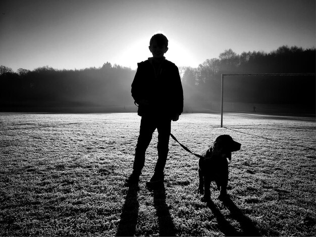 Photo vue arrière d'un garçon avec un chien debout sur le terrain