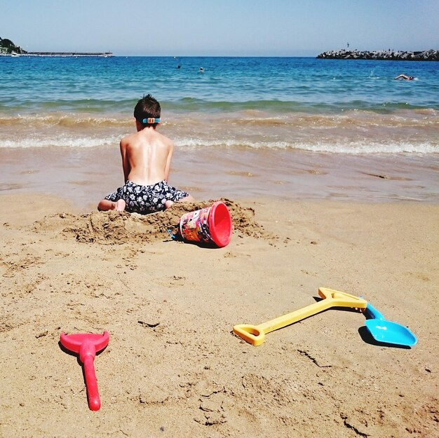 Vue arrière d'un garçon jouant sur le sable de la plage