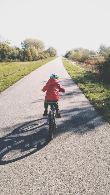 Photo vue arrière d'un garçon à vélo sur la route