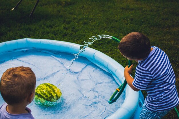 Vue arrière de garçons remplissant d'eau la piscine