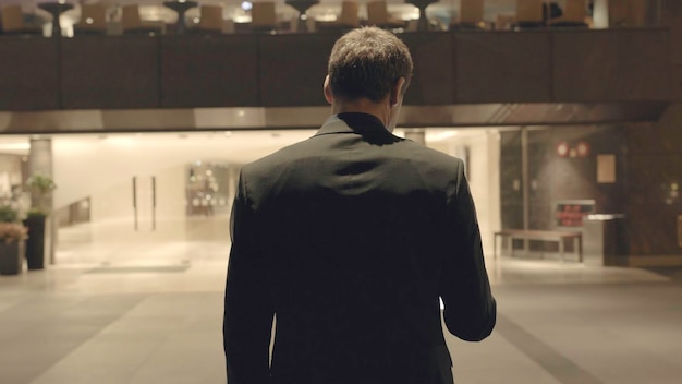 Vue arrière d'un homme d'affaires près de la réception stock il y a des bureaux de mur de verre vue arrière de