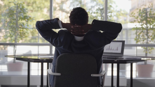 Vue arrière de l'homme d'affaires travaillant au bureau et s'étirant au bureau