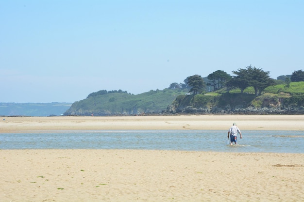Photo vue arrière d'un homme âgé portant un seau dans la rivière à la plage