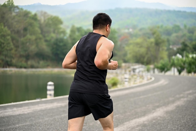 Vue arrière d'un homme asiatique mature en forme de vêtements de sport court dans un parc public