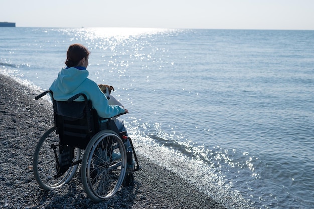 Vue arrière d'un homme assis sur la mer contre le ciel