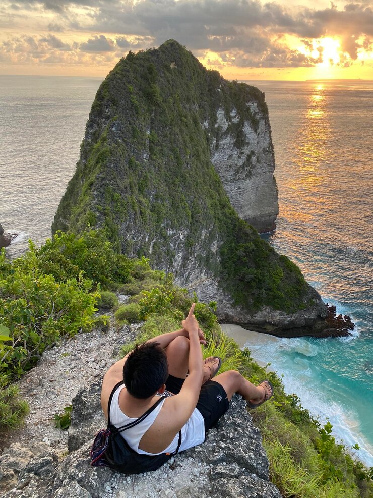Photo vue arrière d'un homme assis sur un rocher contre le ciel