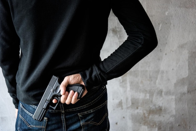 Vue arrière homme atteignant une arme à main attachée, vol qualifié, crime, enlèvement