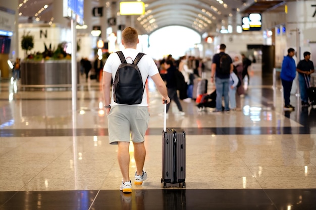 Vue arrière d'un homme blond caucasien d'âge moyen portant des vêtements décontractés tenant un sac à dos de valise à l'aéroport voyageant un touriste en vacances conceptCopyspace pour texte Full body shot
