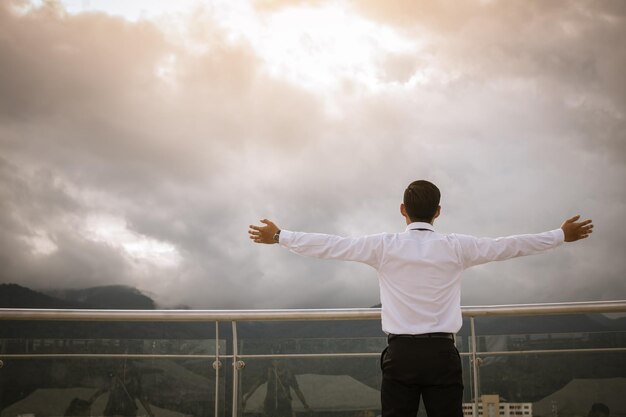 Photo vue arrière d'un homme avec les bras tendus debout contre le ciel