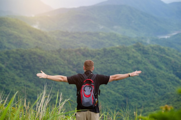 Vue arrière d'un homme avec les bras tendus debout contre les montagnes