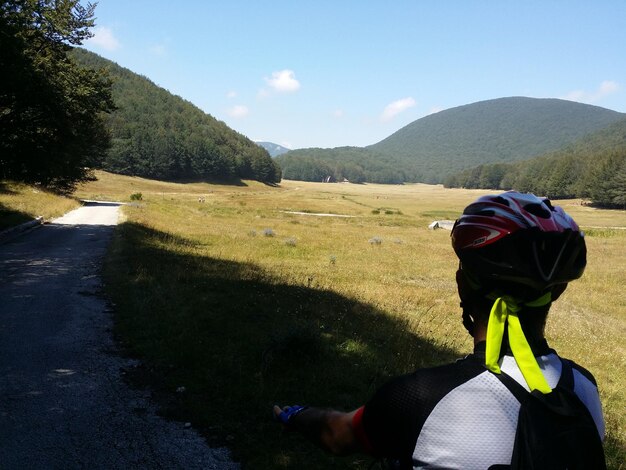 Photo vue arrière d'un homme avec un casque de vélo sur le paysage contre le ciel