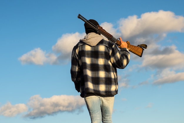 Vue arrière. Homme chasseur avec fusil de chasse.