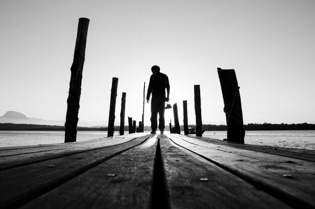 Photo vue arrière d'un homme debout au milieu de la mer sur le quai