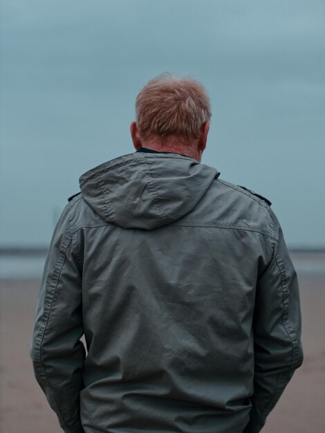 Photo vue arrière d'un homme debout contre la mer contre le ciel