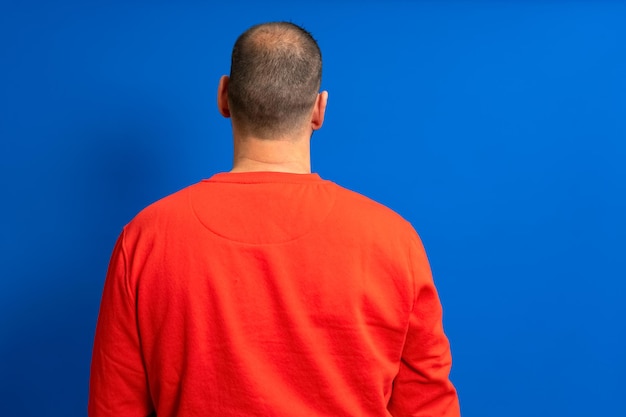 Photo vue arrière d'un homme debout sur un fond bleu