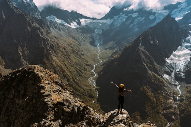 Vue arrière d'un homme debout sur fond de montagnes, les bras tendus. L'homme dans les montagnes lève les mains. L'homme sur le fond des montagnes. Voyage à la montagne