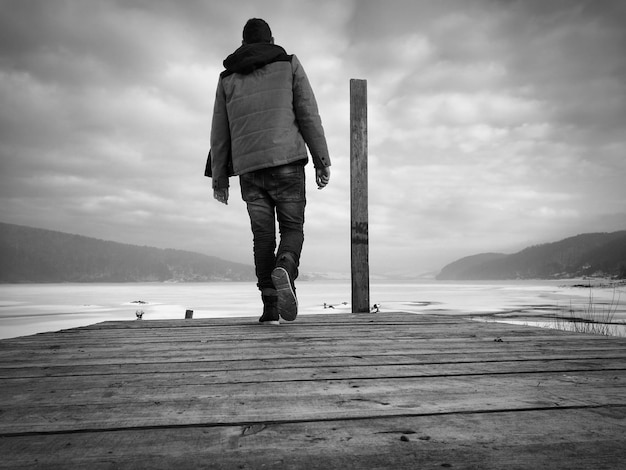 Photo vue arrière d'un homme debout sur une jetée au-dessus de la mer