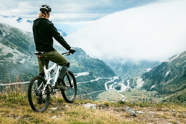 Vue arrière d'un homme debout sur une montagne avec un vélo