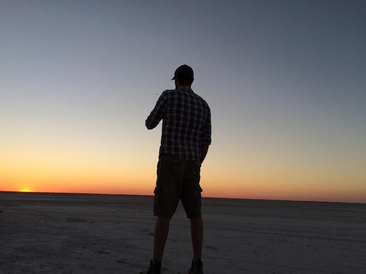 Photo vue arrière d'un homme debout sur la plage contre un ciel clair