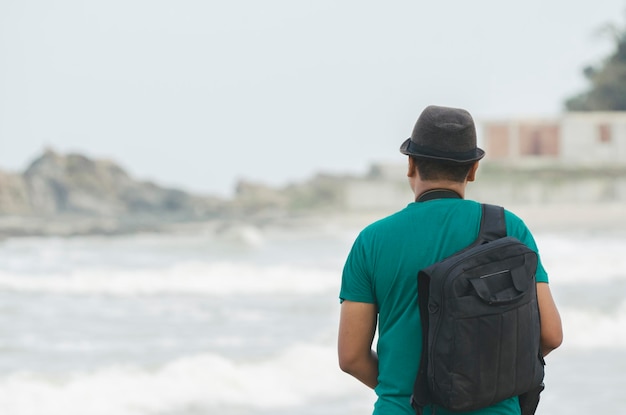 Vue arrière d'un homme debout sur la plage contre le ciel