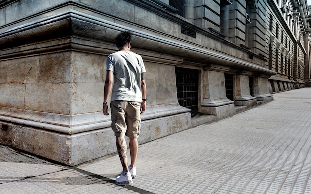 Vue arrière d'un homme debout sur le trottoir contre un bâtiment