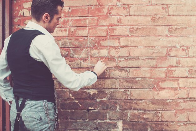 Photo vue arrière d'un homme dessinant sur un mur de briques