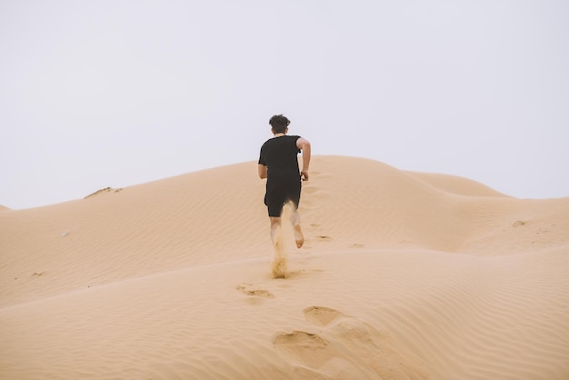Vue arrière d'un homme sur une dune de sable dans le désert