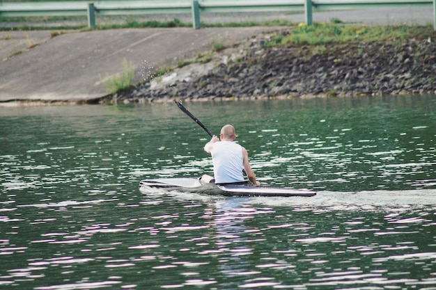 Photo vue arrière d'un homme faisant du kayak dans un lac