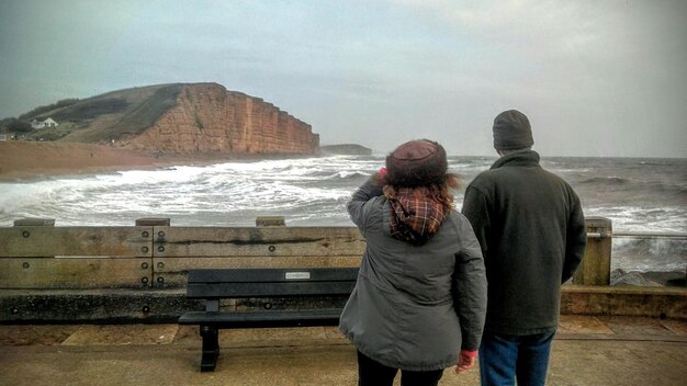 Photo vue arrière d'un homme et d'une femme contre la mer et le ciel