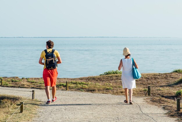 Photo vue arrière d'un homme et d'une femme marchant sur un sentier menant vers la mer