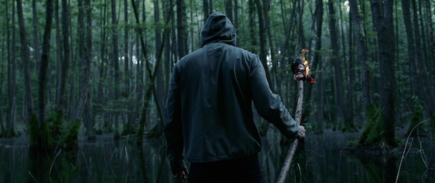 Photo vue arrière d'un homme avec un feu sur du bois debout dans la forêt