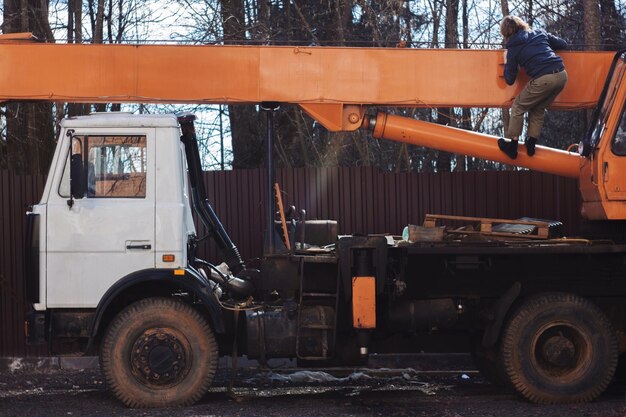 Photo vue arrière d'un homme grimpant sur une grue orange