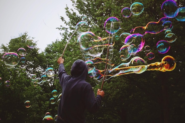 Photo vue arrière d'un homme jouant avec des bulles