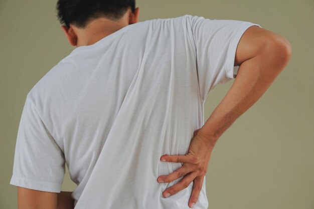 Photo vue arrière d'un homme avec des maux de dos debout contre le mur