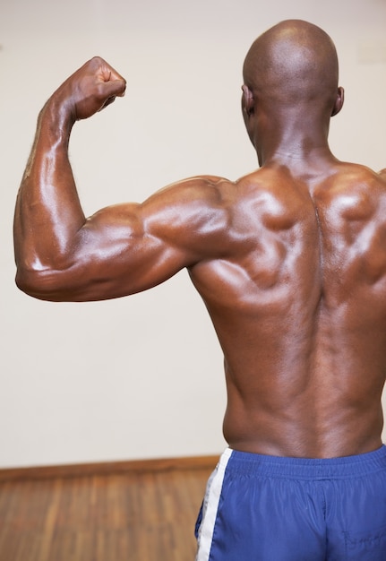 Photo vue arrière d'un homme musclé torse nu qui fléchit les muscles