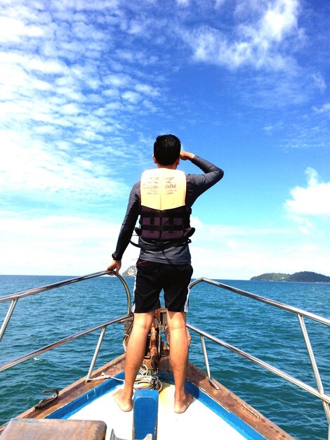 Vue arrière d'un homme naviguant sur la mer contre le ciel