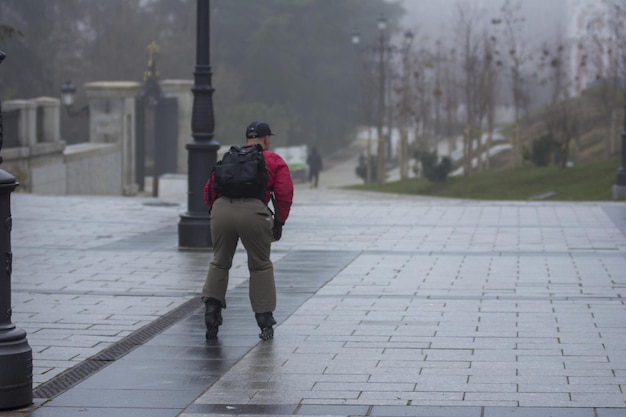 Vue arrière d'un homme patinant dans une rue brumeuse