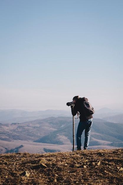 Vue arrière d'un homme photographiant depuis la montagne contre un ciel dégagé