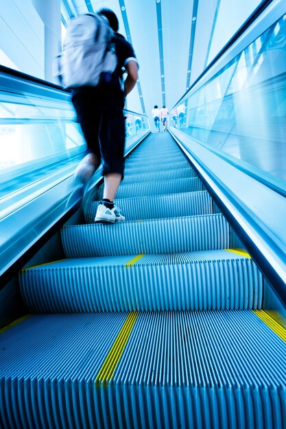 Photo vue arrière d'un homme qui marche sur un escalier mécanique