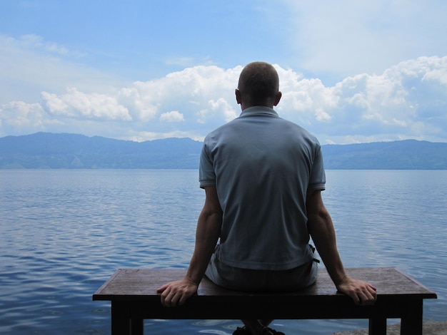 Photo vue arrière d'un homme regardant le lac contre le ciel