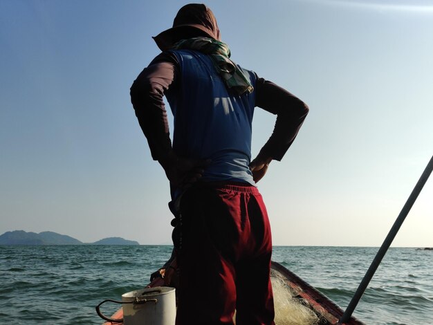 Photo vue arrière d'un homme regardant la mer contre le ciel