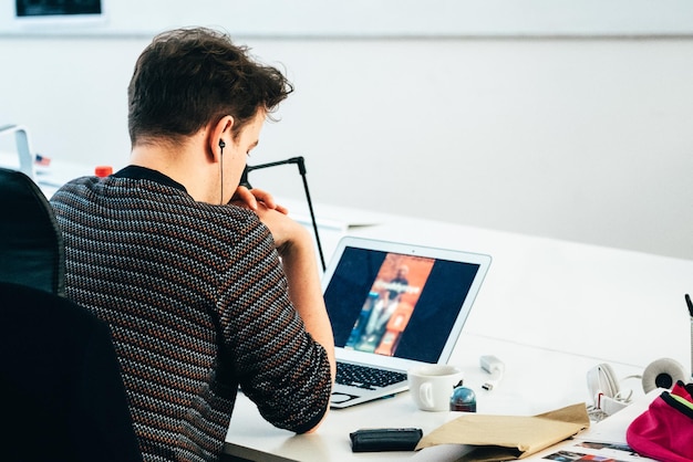 Vue arrière d'un homme regardant un ordinateur portable sur la table