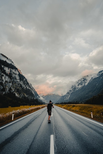 Vue arrière d'un homme sur la route contre un ciel nuageux