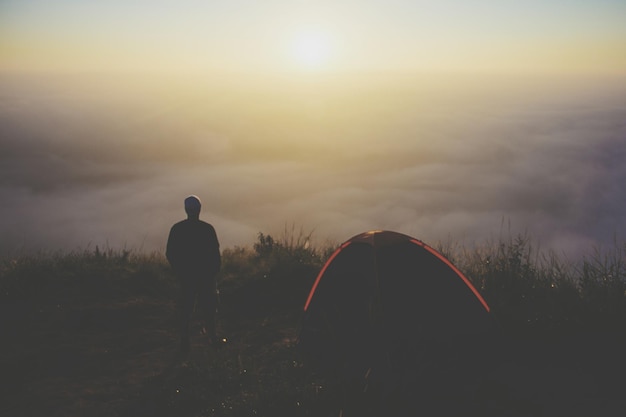 Vue arrière d'un homme en silhouette debout contre le ciel au coucher du soleil.