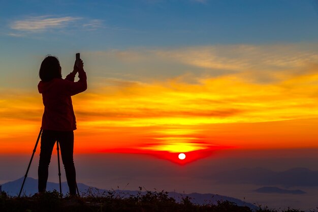 Photo vue arrière d'un homme en silhouette photographiant contre le ciel au coucher du soleil