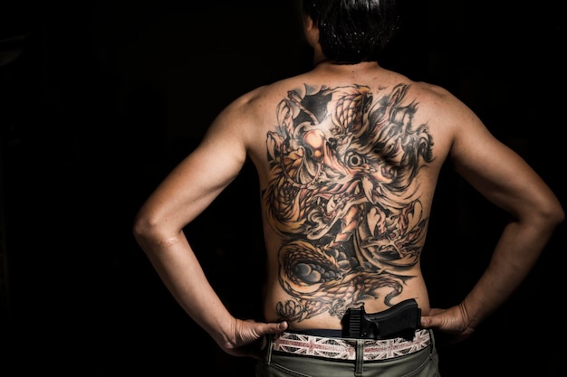 Vue arrière d'un homme tatoué avec une arme