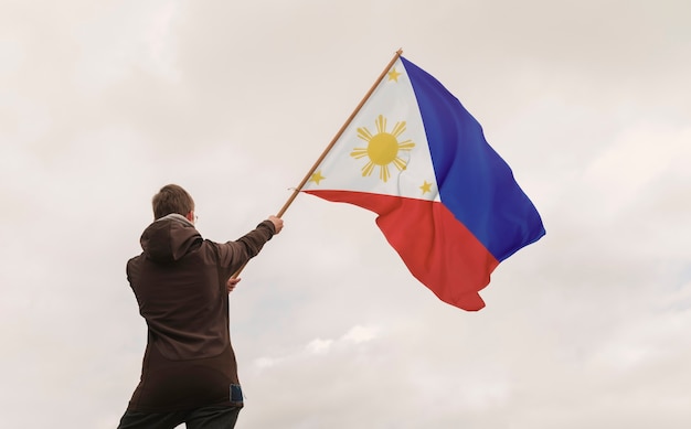 Photo vue arrière homme tenant le drapeau philippin