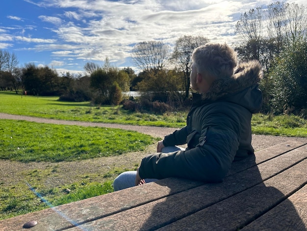 Photo vue arrière d'un homme en train de profiter d'une journée ensoleillée dans le parc assis à une table de pique-nique