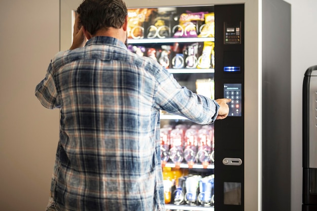 Vue arrière d'un homme utilisant un distributeur automatique