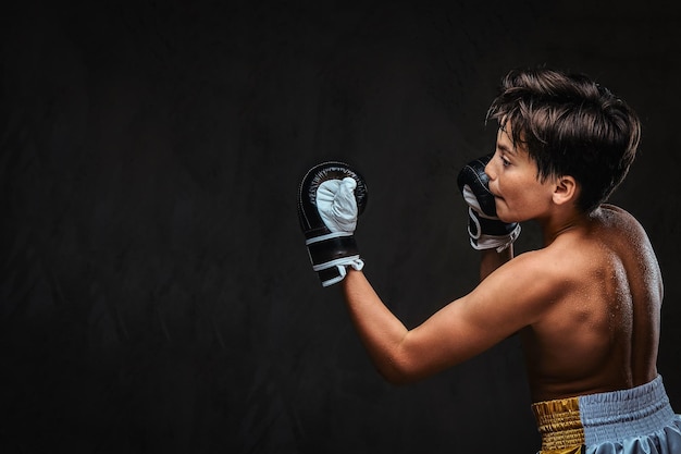 Photo vue arrière d'un jeune boxeur torse nu pendant les exercices de boxe, concentré sur le processus avec un soin du visage concentré sérieux.